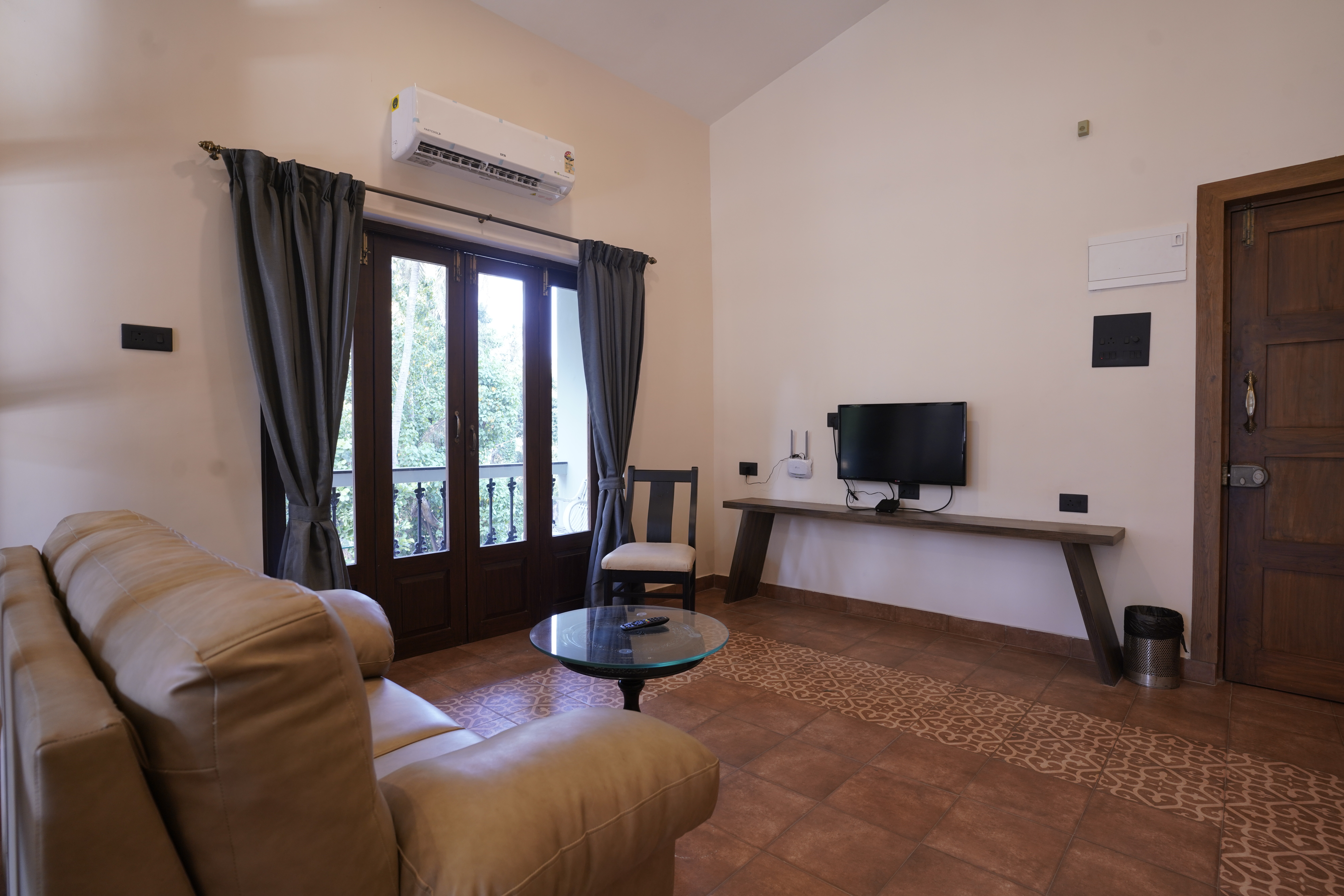 Living area at Hotel Lotus Candolim with a sofa, television and balcony doors
